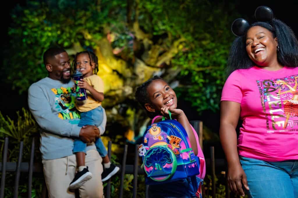 Colorful Disney-themed backpacks and family enjoying a night at Disney park.