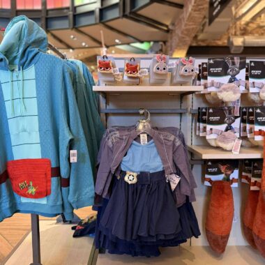 Colorful Disney-themed clothing and plush slippers display at Disney store, featuring characters from Zootopia and other Disney movies.