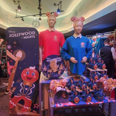 Brightly lit display featuring Disney Hollywood Nights merchandise, including mannequins adorned with unique accessories and themed souvenirs.