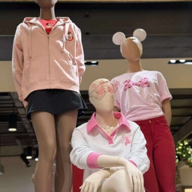 Mannequins showcase Disney-inspired casual outfits with holiday accessories and themed apparel.