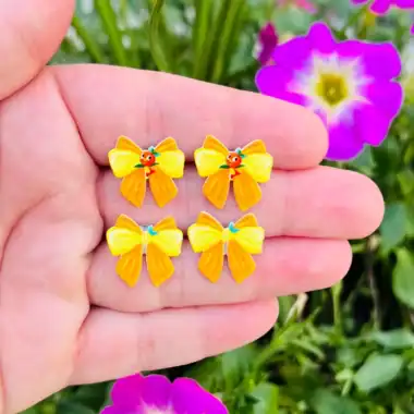 Bright yellow bow earrings with Disney character accents, perfect for fans.