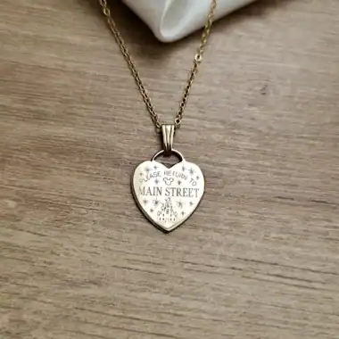 Gold heart necklace with "Please Return to Main Street" engraving, elegant jewelry piece.