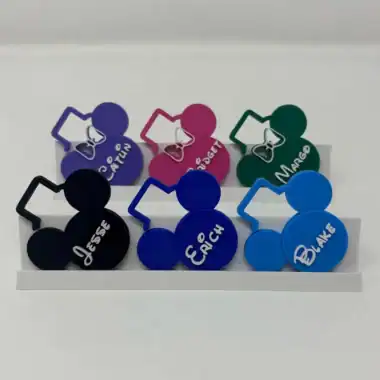 Colorful Disney-themed custom nametags for resort mugs, featuring characters and names.
