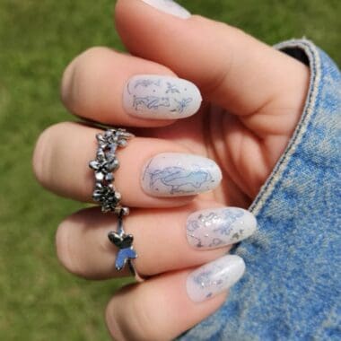 Nail art with Disney characters and ocean themes on white nails.