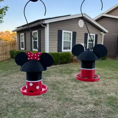 Minnie Mouse themed bird feeders hanging in a backyard.