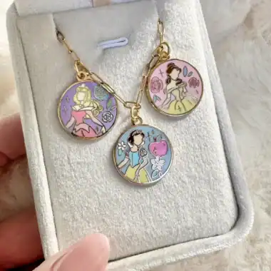 Disney themed jewelry set with three colorful charms in a white box.